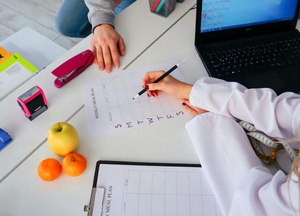 A nutritionist and a patient discuss a weekly meal plan in a modern office setting.